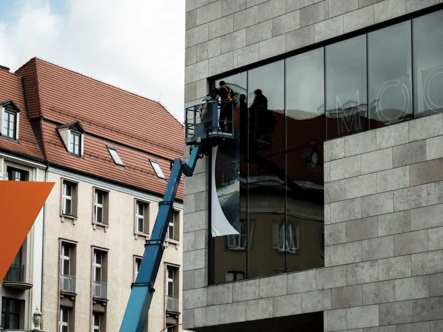 A man cleaning skyscraper windows with a harness, showcasing urban high-rise work.